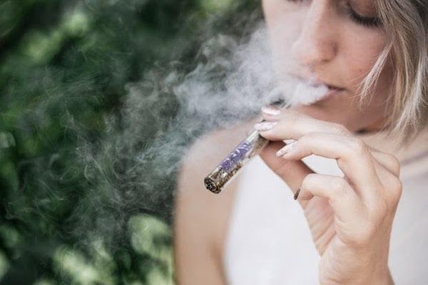 image of woman smoking a blunt or joint; Photo by Grav on Unsplash