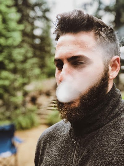 image of man exhaling smoke after learning how to dab; Photo by Andre Guerra on Unsplash